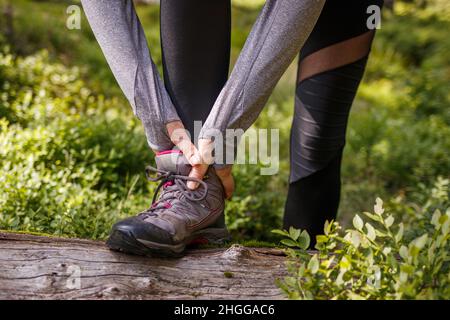 Verstauchung des Knöchels beim Wandern in der Natur. Frau, die nach einer Unfallverletzung im Freien Schmerzen spürt Stockfoto