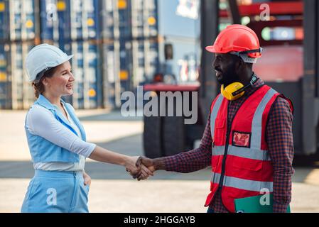 Happy Dealing schüttelt die Hände zwei Geschäftsfrau und Ingenieur arbeiten Überprüfung Verladecontainer Box von Cargo Frachtschiff für Import-Export. Shipping Stockfoto