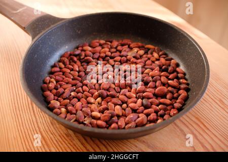 Gebratene Erdnüsse in einer Pfanne auf einem Holztisch. Stockfoto