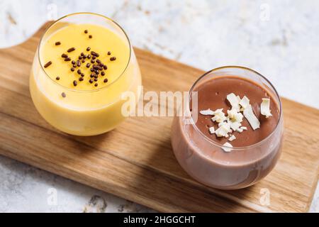 Pudding aus Vanille und Schokolade mit Schokoladenbröseln, Sternanise. Platziert auf weißem rustikalem Brett. Stockfoto