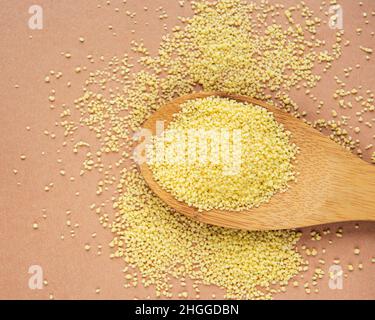 Roher Couscous in einem Holzlöffel auf braunem Hintergrund Stockfoto