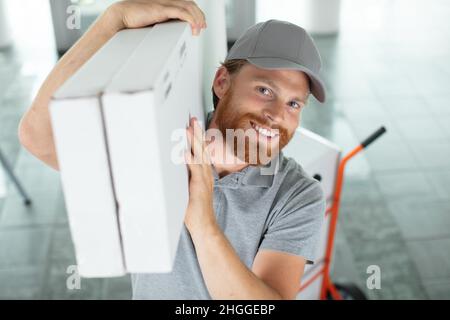 Junger Mann, der in Umzugsdiensten mit Kisten arbeitet Stockfoto