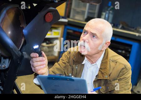 Leitender Mechaniker überprüft die Bremsen eines klassischen Motorrads Stockfoto