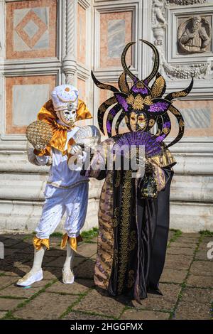 Teilnehmer in farbenfrohem arlecchino Harlekin Wahrsager Kostüm und mythischem orientalischen Outfit Pose, Carnevale Di Venezia, Karneval in Venedig, Italien Stockfoto