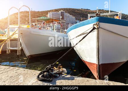 Reihe von vielen kleinen alten hölzernen vintage bunten hellen Fischerschiffen, die an Fischerdorf Marina klaren Wasserbucht an hellen sonnigen Tag festgemacht werden. Seehafen Stockfoto