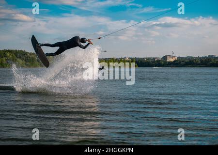 Wakeboarder üben Tricks springen an Bord über Wasseroberfläche schaffen Spritzer Stockfoto