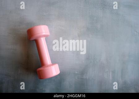 Fitness- und Gewichtsmanagement-Konzept. Rosa Kurzhantel auf Betonboden mit Platz für Text Stockfoto