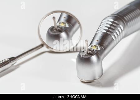 High-Speed-Zahnarzthandstück und Metallspiegel auf weißem Hintergrund. Zahnärztliche Instrumente für die zahnärztliche Behandlung. Medizinische Werkzeuge. Nahaufnahme. Geringe Tiefe Stockfoto