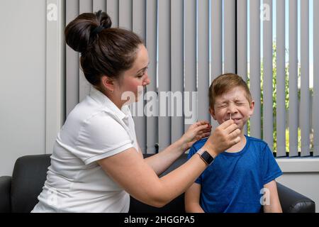 Mutter führt den COVID-19-Schnellantigen-Test für ihren Sohn durch Stockfoto