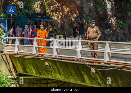 ELLA, SRI LANKA - 27. DEZEMBER 21: Mönch und Polizist an den Ravana Wasserfällen Ella, in der Nähe von Ella Town, Sri Lanka Stockfoto