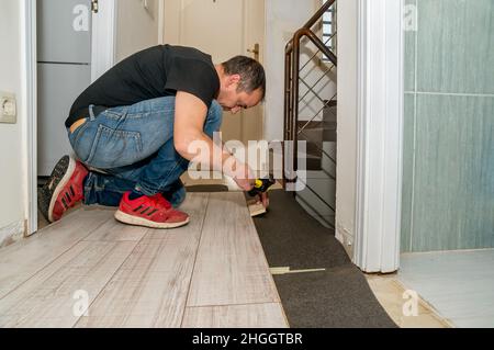 Arbeiter mit amputierten Fingern. Tagsüber arbeitet er an der Verlegung des Fußbodens in seinem Haus. Stockfoto