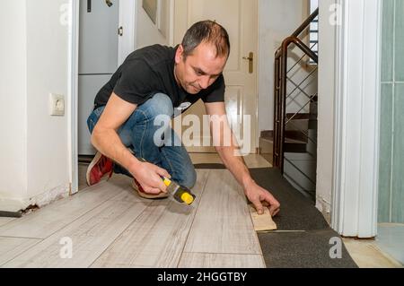 Arbeiter mit amputierten Fingern. Tagsüber arbeitet er an der Verlegung des Fußbodens in seinem Haus. Stockfoto