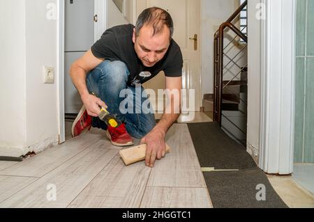 Arbeiter mit amputierten Fingern. Tagsüber arbeitet er an der Verlegung des Fußbodens in seinem Haus. Stockfoto