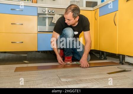 Arbeiter mit amputierten Fingern. Tagsüber arbeitet er an der Verlegung des Fußbodens in seinem Haus. Stockfoto