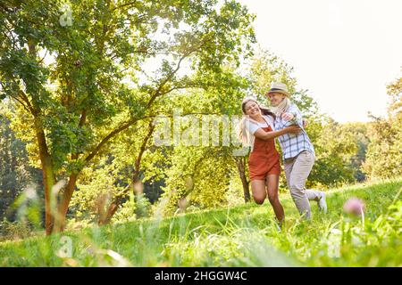 Mutter und Tochter springen und tanzen gemeinsam auf einer Wiese in der Natur Stockfoto