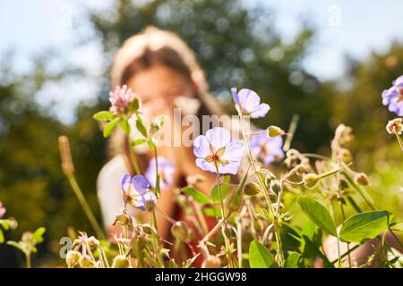 Blühende Blumen im Frühling und Kind mit Heuschnupfen, die Nase im Hintergrund bläst Stockfoto