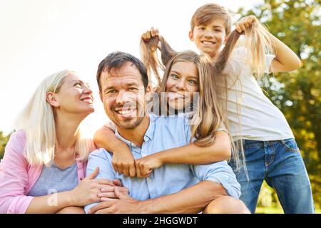 Glückliche Familie im Urlaub und alberne Kinder, die Gesichter machen und Haare ziehen Stockfoto