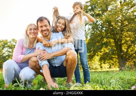 Glückliche Familie und zwei Kinder in der Natur im Sommer machen Unfug und Herumtäuschen Stockfoto