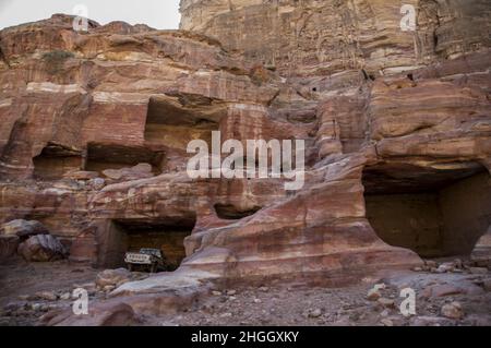Toyota Pickup-Trucks parkten in alten nabateischen Strukturen in Petra, Jordanien, inmitten von Schluchten, Höhlen, Wüstenlandschaft und Gebäuden. Stockfoto