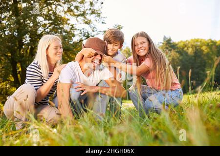 Kinder haben Spaß auf einem Sommer-Naturausflug und necken ihren Vater Stockfoto