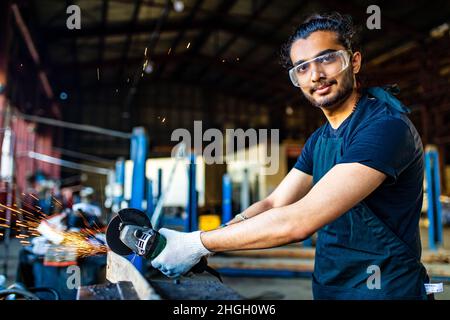 lateinischer hispanischer Automechaniker in Uniform untersucht ein Auto, während er im Autodienst arbeitet Stockfoto