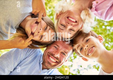 Alberne Kinder ragen aus ihren Zungen und Eltern lachen als glückliche Familie Stockfoto