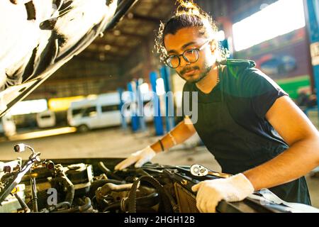 indischer Mann Auto Mechaniker arbeiten drinnen in Autogeschäft Stockfoto