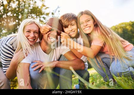 Kinder machen Unfug und necken ihren Vater auf einem sommerlichen Naturausflug Stockfoto