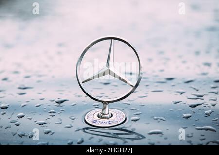 Nahansicht Des Metallsternlogos Von Mercedes Benz Auf Der Feuchten Haube Des Blauen Autos Nach Dem Regen. Stockfoto