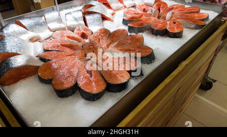 Frisches, rohes Lachssteak auf Eis an der Theke in einem Fischgeschäft. Rote Fischsteaks werden im Supermarkt verkauft. Stockfoto