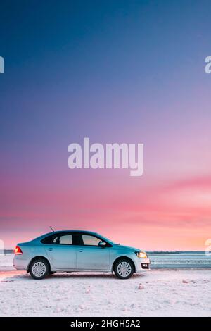 Volkswagen Polo Auto Limousine Parken auf Einer Straße der Country Road auf Einem Hintergrund des dramatischen Sonnenuntergang Himmel in der Wintersaison Stockfoto