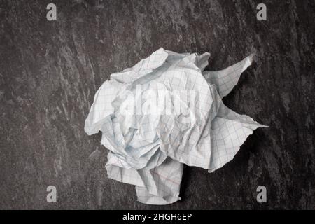 Zerknittertes und zerrissenes Papier auf dem Tisch. Zerrissenes Notizbuch. Papiermüll. Voller Korb mit Notizen. Notizblock und Bleistift auf zerknittertem Papierhintergrund. Stockfoto