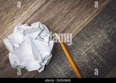 Zerknittertes und zerrissenes Papier auf dem Tisch. Zerrissenes Notizbuch. Papiermüll. Voller Korb mit Notizen. Notizblock und Bleistift auf zerknittertem Papierhintergrund. Stockfoto
