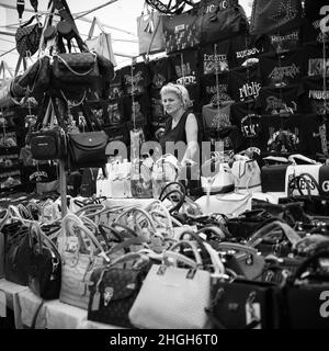 Sokobanja, Serbien, 19. Aug 2021: Eine Verkäuferin steht neben einem Stand mit Geldbörsen auf einem Dorfmarkt Stockfoto