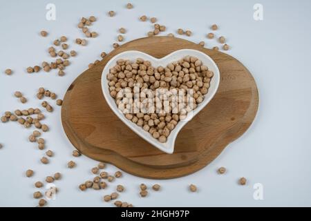 Rohe Kichererbsen auf dem herzförmigen Teller und Handtuch. Draufsicht. Stockfoto