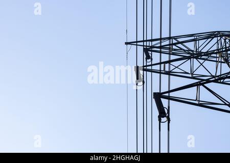 Nahaufnahme der Unterseite des Kabelaufhängungsarms des elektrischen Übertragungsturms unter dem klaren blauen Himmel mit Kopierfläche Stockfoto