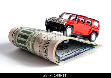 Ein Nahaufnahme-Modell eines schönen Autos steht auf einem Stapel amerikanischer Dollarscheine isoliert auf weißem Hintergrund. Stockfoto