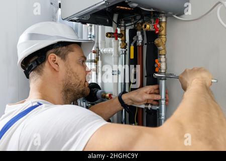 Arbeiter, der Rohre des Hausgasheizkessels installiert Stockfoto