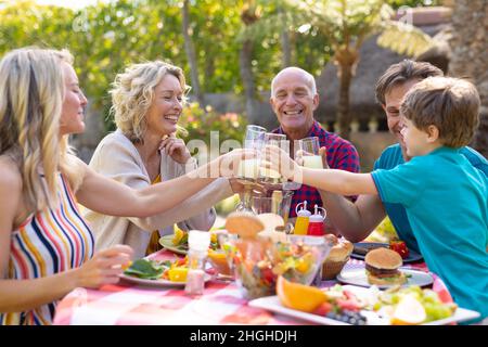 Glücklicher Kaukasier drei Generationen Familie Toasting Getränke am Tisch im Garten Stockfoto