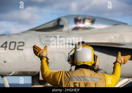 PAZIFISCHER OZEAN (Jan 17, 2022) Aviation Boatswain's Mate (Handling) 1st Klasse Melvin Dominguez aus Tujena, Kalifornien, leitet einen F/A-18E Super Hornet, der den „Vigilanten“ des Strike Fighter Squadron (VFA) 151 zugewiesen wurde, auf dem Flugdeck der USS Abraham Lincoln (CVN 72). Die Abraham Lincoln Strike Group befindet sich im geplanten Einsatzgebiet der US-Flotte für 7th, um die Interoperabilität durch Allianzen und Partnerschaften zu verbessern und gleichzeitig als reaktionsfähige Truppe zur Unterstützung einer freien und offenen Region im Indo-Pazifik-Raum zu dienen. Stockfoto