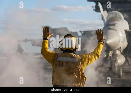 PAZIFISCHER OZEAN (Jan 17, 2022) Aviation Boatswain's Mate (Handling) 1st Klasse Melvin Dominguez aus Tujena, Kalifornien, leitet einen F/A-18E Super Hornet, der den „Vigilanten“ des Strike Fighter Squadron (VFA) 151 zugewiesen wurde, auf dem Flugdeck der USS Abraham Lincoln (CVN 72). Die Abraham Lincoln Strike Group befindet sich im geplanten Einsatzgebiet der US-Flotte für 7th, um die Interoperabilität durch Allianzen und Partnerschaften zu verbessern und gleichzeitig als reaktionsfähige Truppe zur Unterstützung einer freien und offenen Region im Indo-Pazifik-Raum zu dienen. Stockfoto