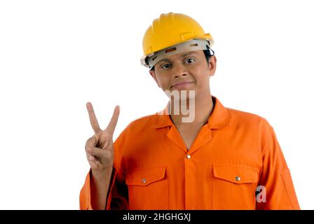 Mumbai Maharashtra Indien- Asien Dez. 26 2009 - glücklicher indischer hübscher junger Arbeiter, der Uniform und Helm trägt und ein Siegeszeichen auf weißem Hintergrund zeigt Stockfoto
