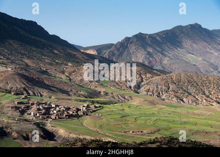 Das Atlasgebirge in Marokko. Berber Dorf am Fuße eines Tals, umgeben von terrassenförmigen Pflanzen Stockfoto