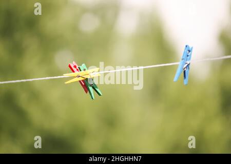 Bunte Kunststoff-Wäscheklammern auf dem Seil im Freien. Stockfoto