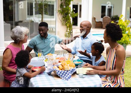 Glückliche afroamerikanische Familie mit drei Generationen, die Brunch im Hinterhof genießt Stockfoto