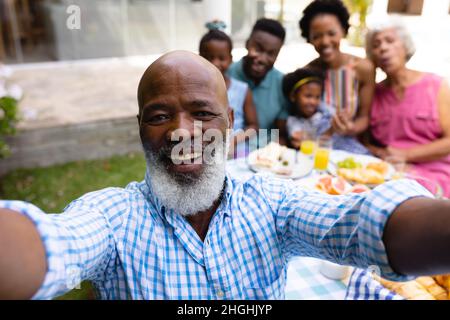 Porträt eines lächelnden, bärtigen, kahlköpfigen afroamerikaners, der beim Brunch mit seiner Familie Selfie gemacht hat Stockfoto