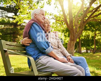 Im Ruhestand in Komfort und Glück. Aufnahme eines glücklichen älteren Paares, das sich auf einer Parkbank entspannt. Stockfoto