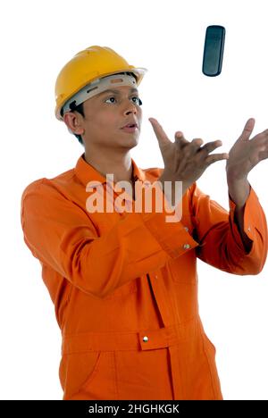 Mumbai; Maharashtra; Indien- Asien; Dec. 26; 2009 - glücklicher, hübscher junger Mann aus indien, der Uniform und Helm trägt und mit dem Mobiltelefon spielt. Stockfoto