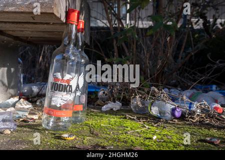 Leere Vodka-Flaschen und andere Abfälle werden am 20th. Januar 2022 in Canning Town, im East End-Bezirk von Newham, in London, England, unter einer Bank weggeworfen. Daten von Public Health England zeigen, dass 468 Menschen in Newham in den Jahren 2017 bis 18 bei Alkoholmissbrauchsdiensten behandelt wurden, etwa einer von 1.000 Personen - ein Aufkommen von 290 Personen, die die Dienste drei Jahre zuvor genutzt haben. Stockfoto