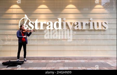 Mit einer Geige vor dem Stradivarius-Bekleidungsgeschäft im Stadtzentrum von Belfast, Nordirland Stockfoto